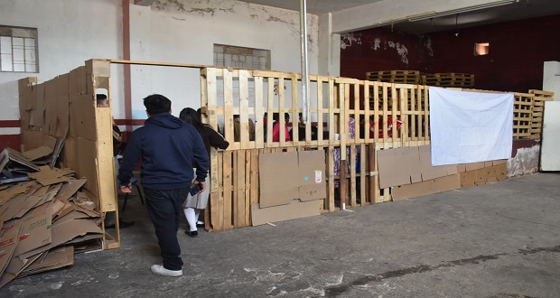 El estudiantado toma clases en aulas construidas con pedazos de maderas y cartón.