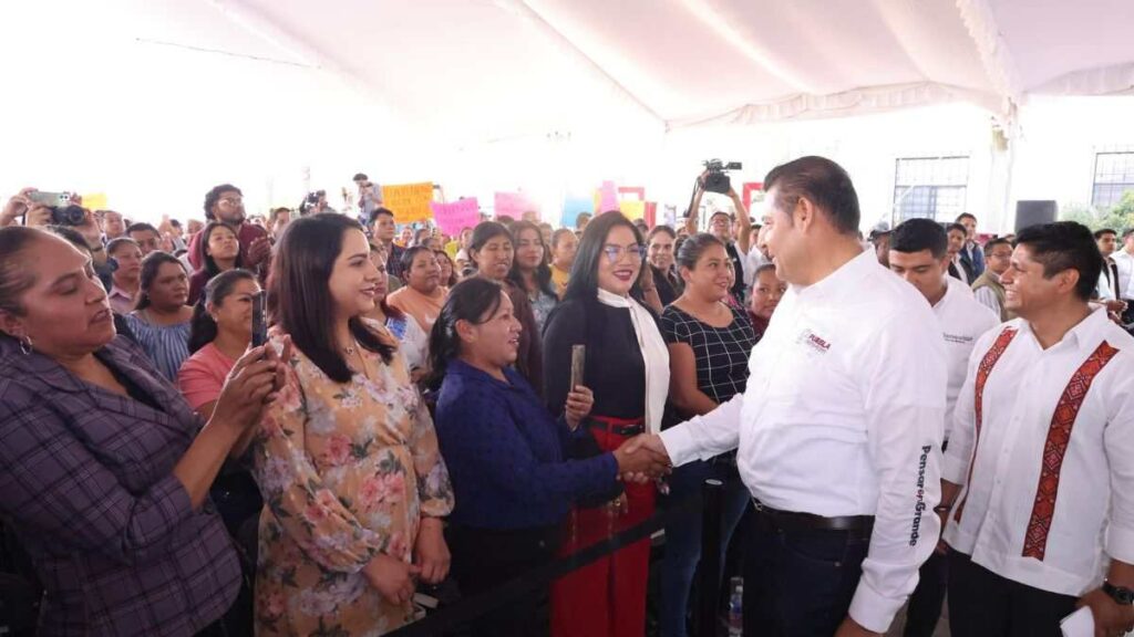 Alejandro Armenta, saludando a una mujer entre una multitud, durante un evento público.